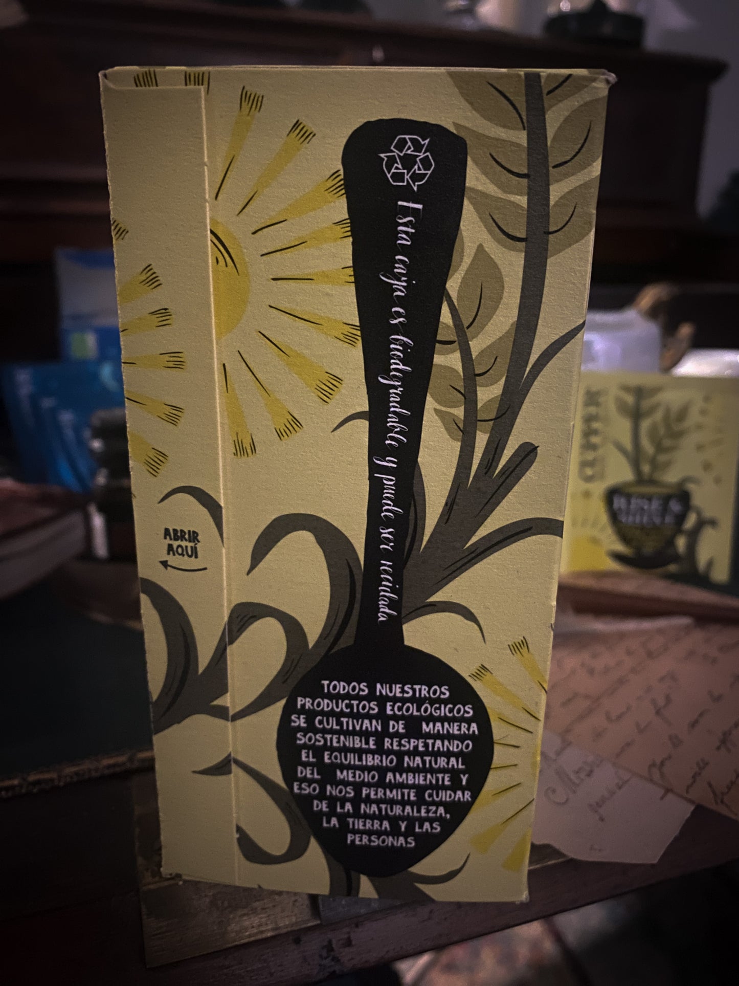 Un momento di relax con una tazza di tisana Cupper, circondata da pacchetti di tè vari assortiti, sullo sfondo di un'ambientazione accogliente con note scritte a mano e una penna stilografica, invitando a una pausa rilassante.