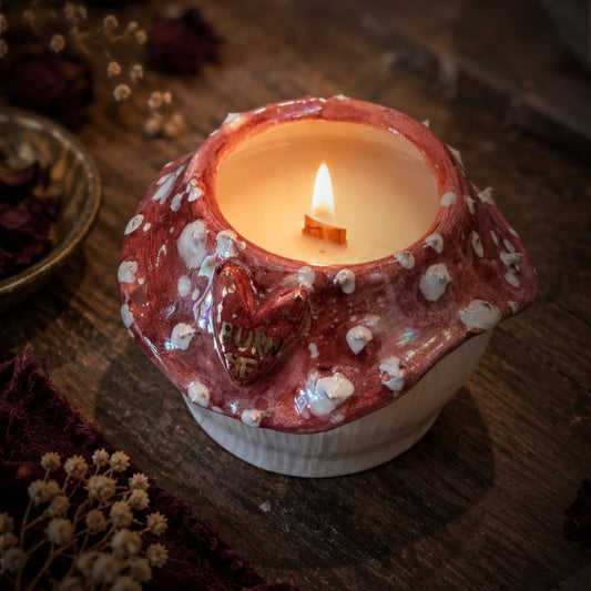 Candela Burn Me accesa con stoppino in legno, cappello rosso a pois bianchi e cuore con scritta in oro