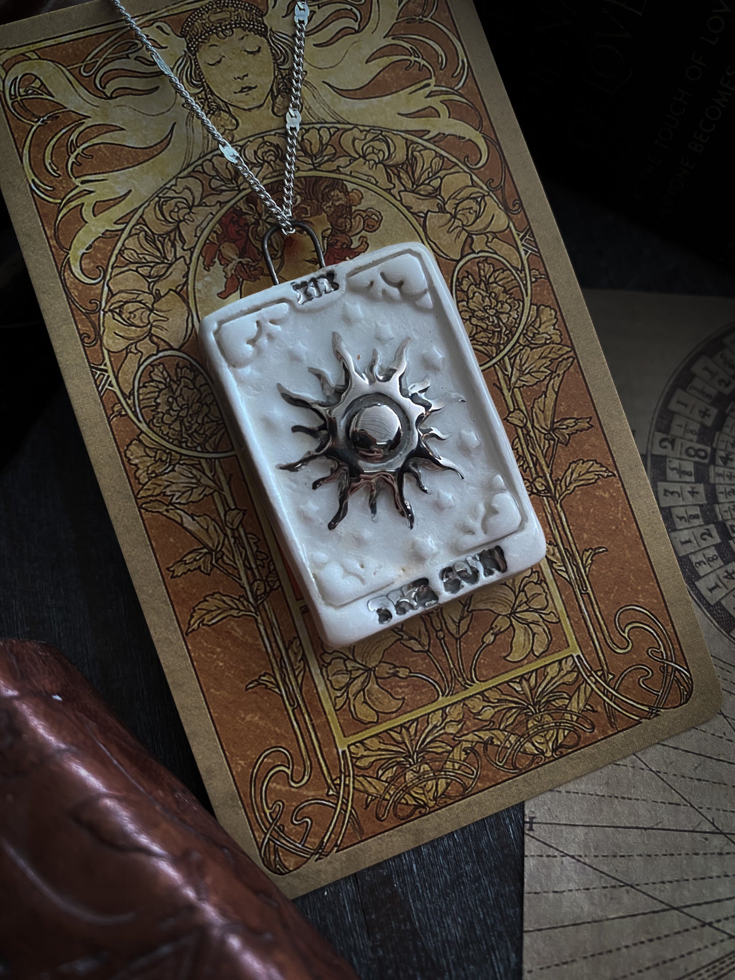 ciondolo collana tarocchi arcano maggiore the sun applicato a una carta tarocchi su un tavolino con oggetti antichi