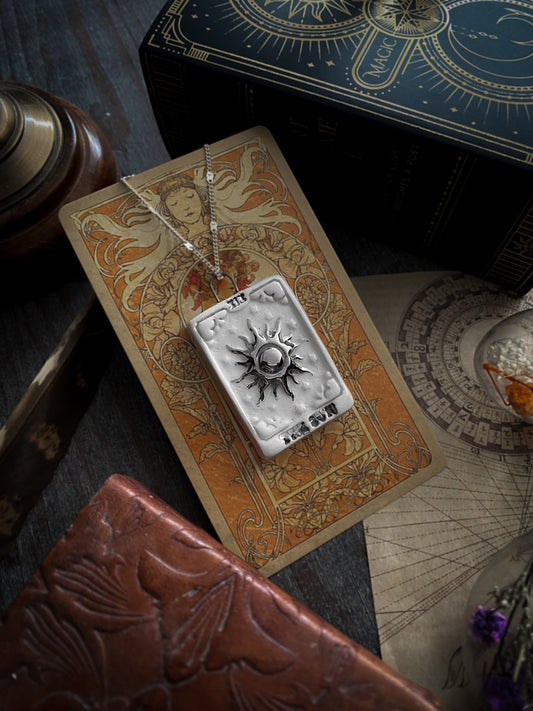 ciondolo collana tarocchi arcano maggiore the sun applicato a una carta tarocchi su un tavolino con oggetti antichi
