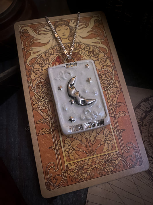 ciondolo carta tarocchi the moon appoggiato su una carta tarocchi di Mucha