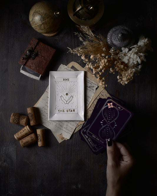 un piattino con carte tarocchi con una mano che tiene una carta in mano