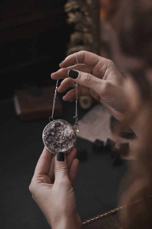 Una donna tiene tra le mani una collana in ceramica a forma di luna piena
