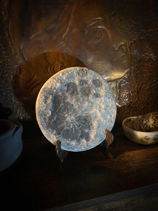Luna piena in ceramica bianca con riflessi azzurro ghiaccio, appoggiata sul suo supporto