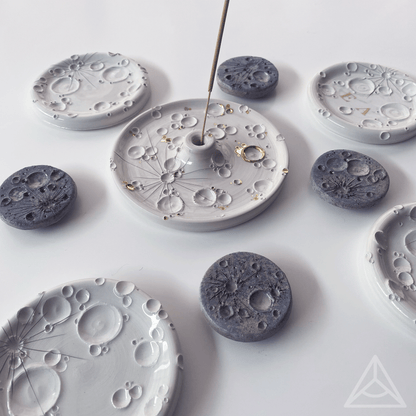 Collezione di porta-incensi in ceramica con vari disegni e texture, con bastoncini di incenso inseriti, su sfondo bianco.