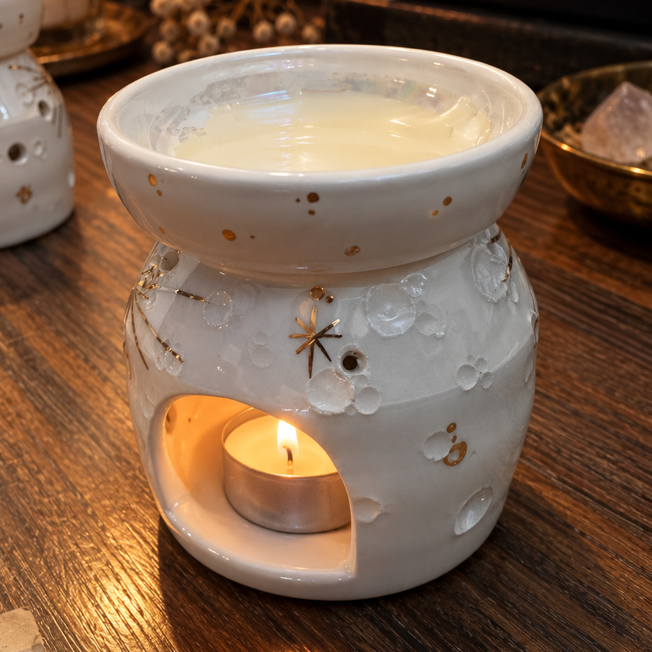 Brucia essenze Moonlight Melt House in ceramica bianca con crateri in oro, acceso con la candelina