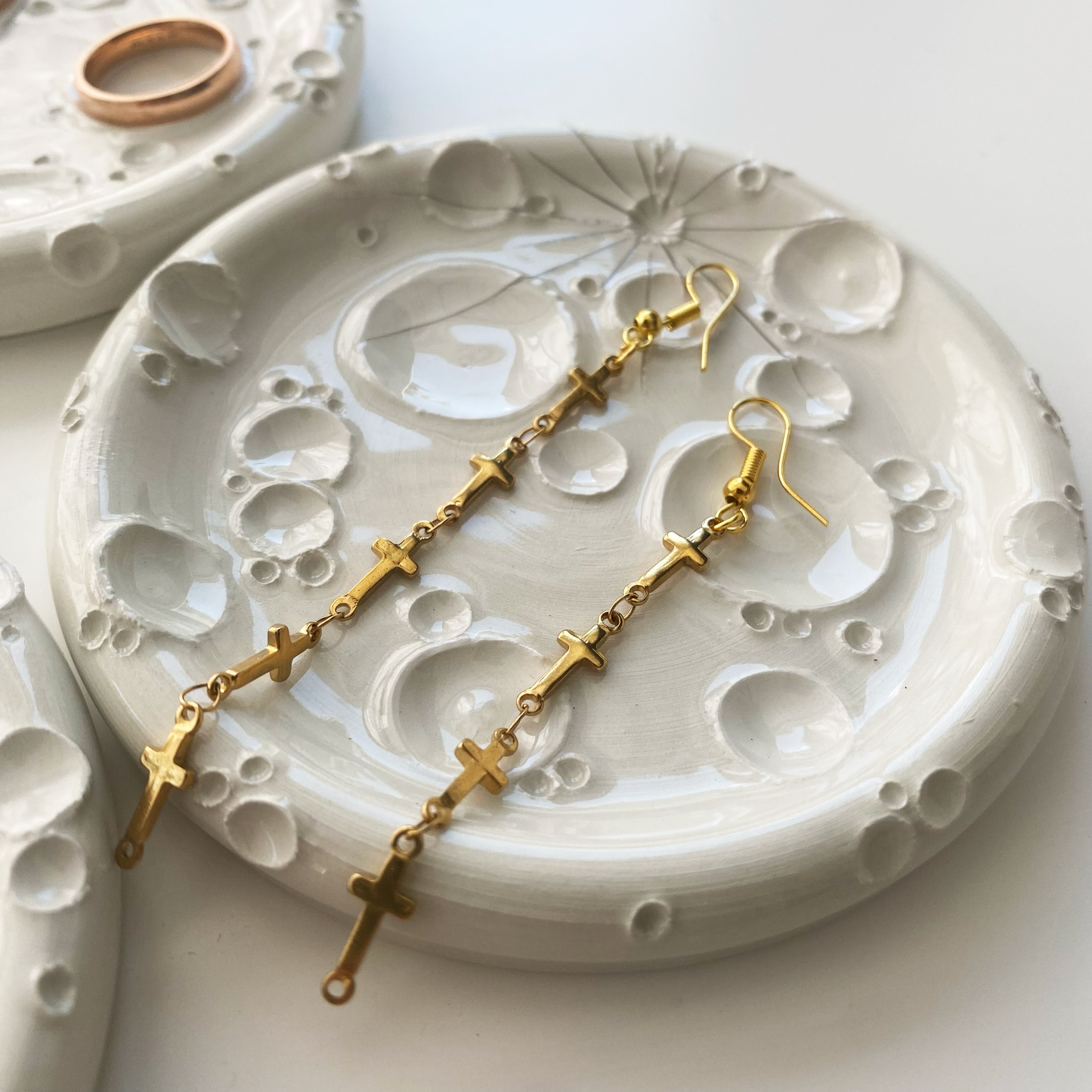 Composizione artistica di porta-incensi in ceramica bianca, ciascuno con design unico, accompagnati da gioielli dorati e ambientazione luminosa.