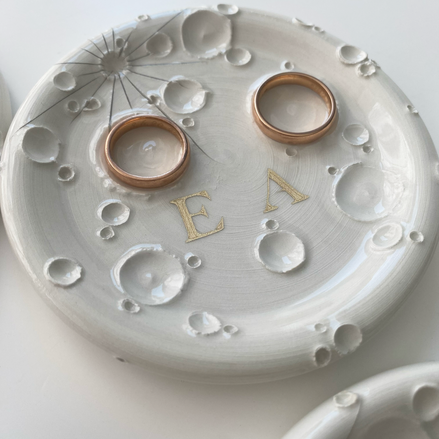 Portafedi in ceramica bianca con lettere personalizzate E e A con due Fedi nuziali appogiate nei solchi della Luna