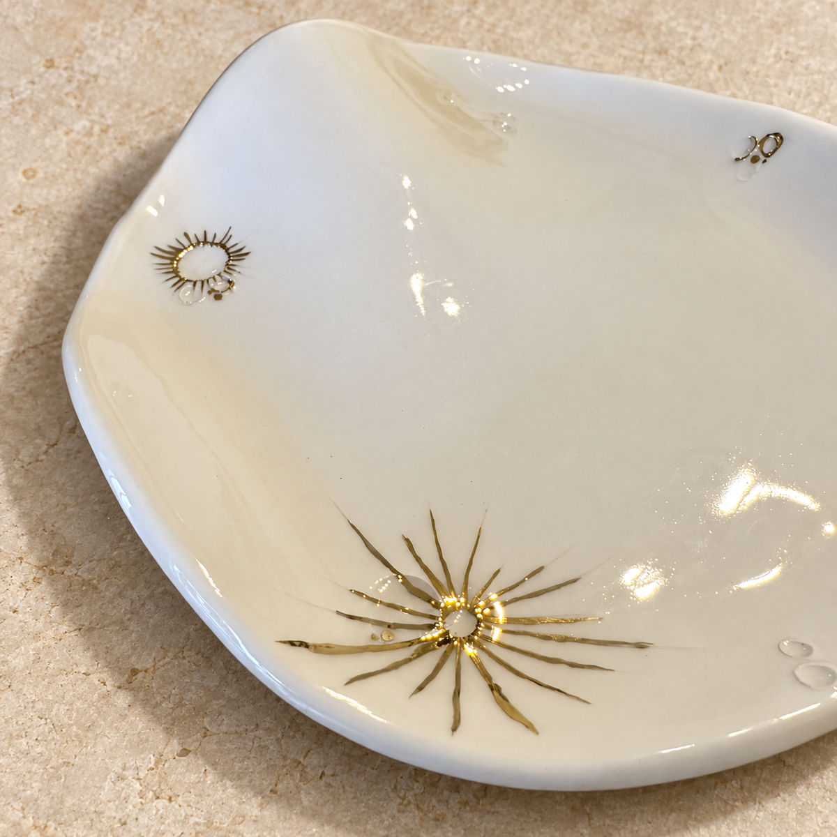 Crateri lunari in lustro oro sul piatto da portata bianco White Lunar Wave, fatto a mano da Ela Ceramics