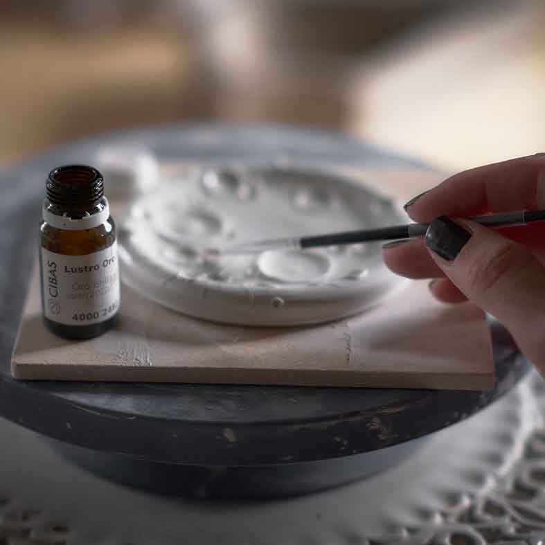 mano con pennellino su pezzo in ceramica