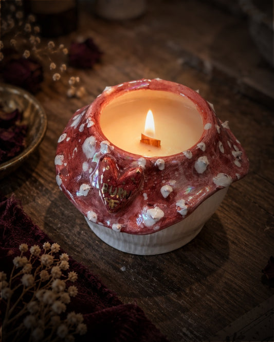 Candela Burn Me accesa con stoppino in legno, cappello rosso a pois bianchi e cuore con scritta in oro