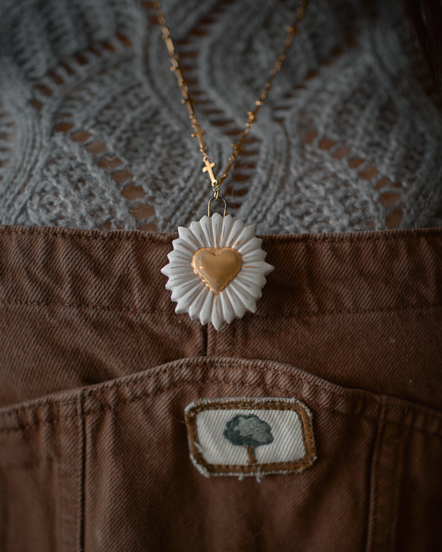 Collana artigianale in ceramica con pendente a cuore, in primo piano davanti a un maglione lavorato a maglia, riflettendo lo stile e la qualità di Ela Ceramics.