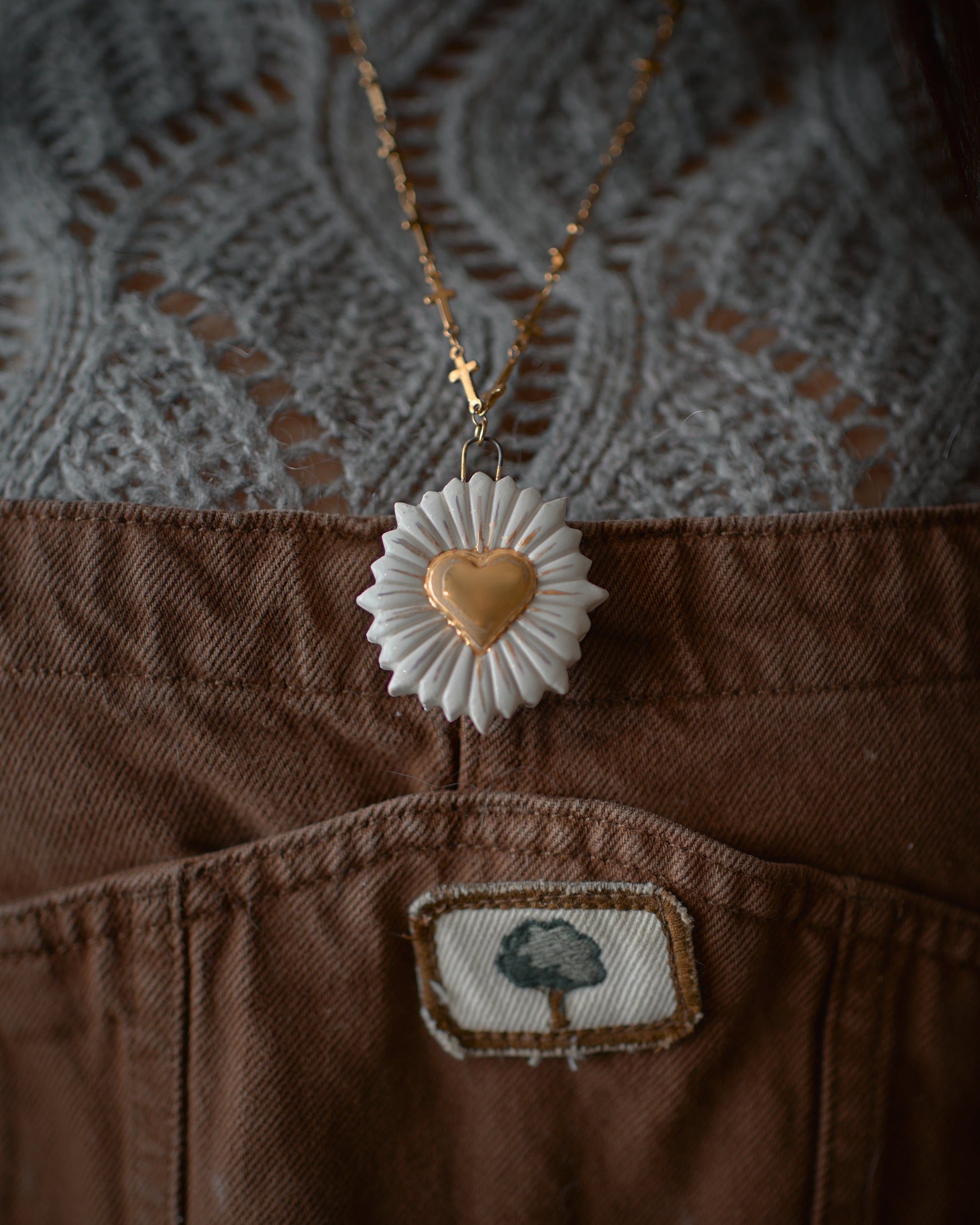 Collana artigianale in ceramica con pendente a cuore, in primo piano davanti a un maglione lavorato a maglia, riflettendo lo stile e la qualità di Ela Ceramics.