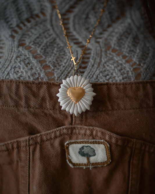 Collana artigianale in ceramica con pendente a cuore, in primo piano davanti a un maglione lavorato a maglia, riflettendo lo stile e la qualità di Ela Ceramics.