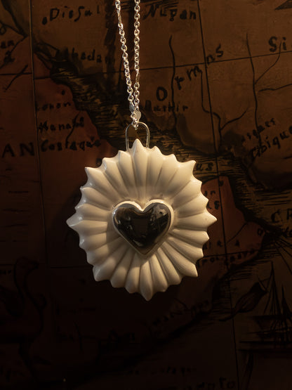ravvicinato collana a forma di cuore sacro con cuore in platino appesa su un mappamondo vintage