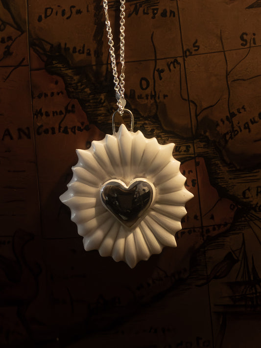 ravvicinato collana a forma di cuore sacro con cuore in platino appesa su un mappamondo vintage
