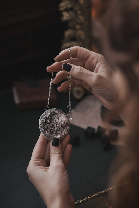 donna che tiene tra le mani una collana in ceramica a forma di luna