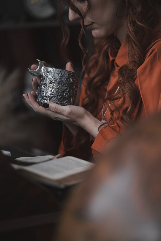 tazza lunare in ceramica da regalo nera con luna tenuta in mano da donna