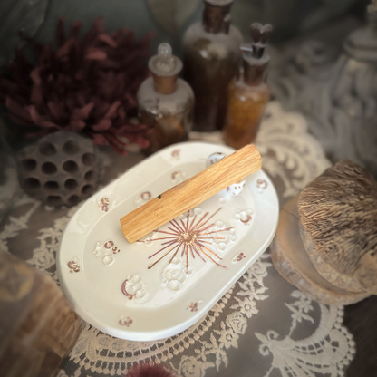 Piattino lunare White and Rose Gold con palo santo, su pizzo e legno tra fiori secchi e boccette vintage.