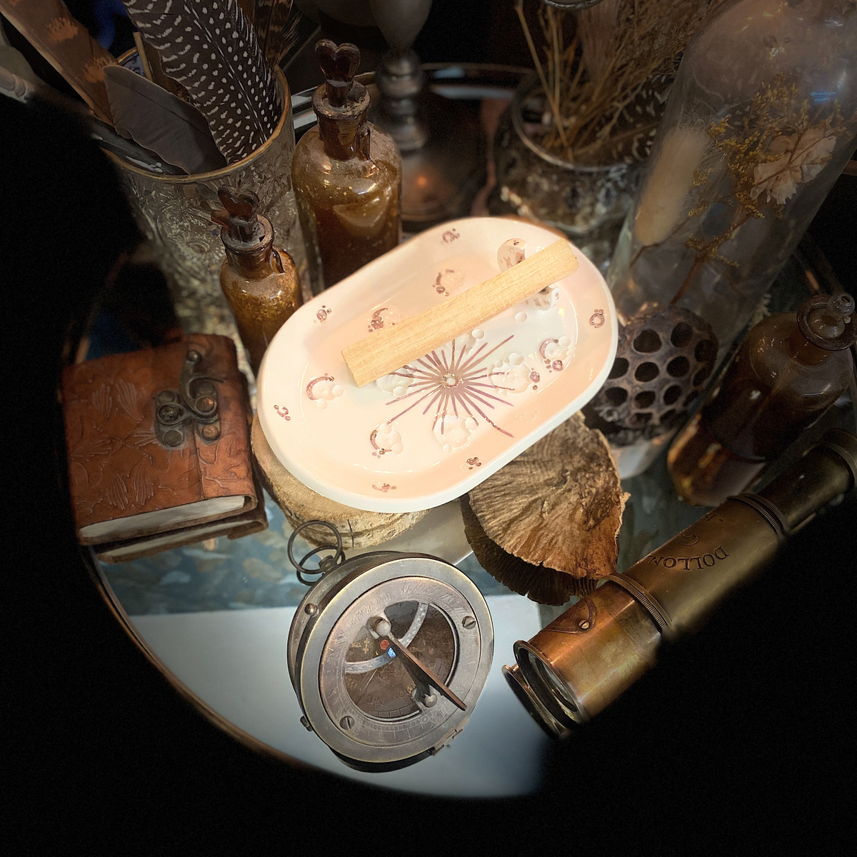 Piattino White and Rose Gold con palo santo in un'ambientazione vintage con libro, bussola e cannocchiale.
