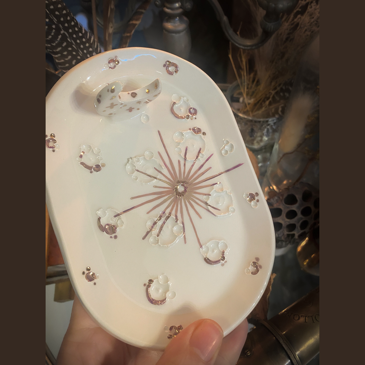 Piattino White and Rose Gold tenuto in mano, dettaglio delle decorazioni lunari in lustro oro rosa.